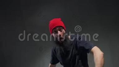 一位戴着红帽子的年轻嘻哈舞者在课堂上表演城市舞蹈。 这个男孩的手在自由泳中移动